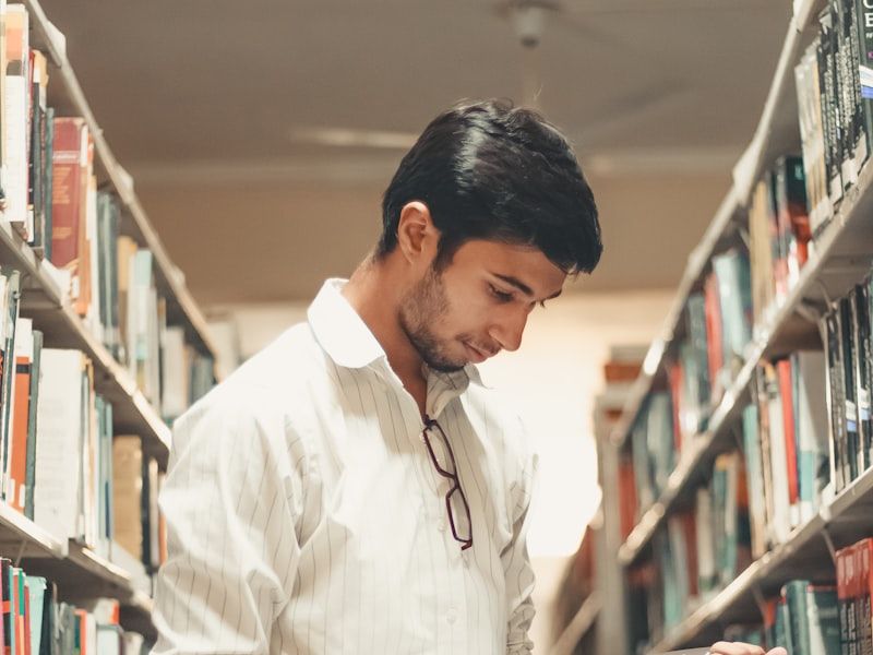 A student reading a book among library shelves
