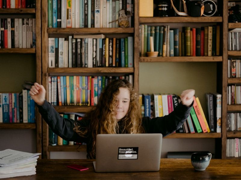 A student celebrating a breakthrough during a live online class on her laptop